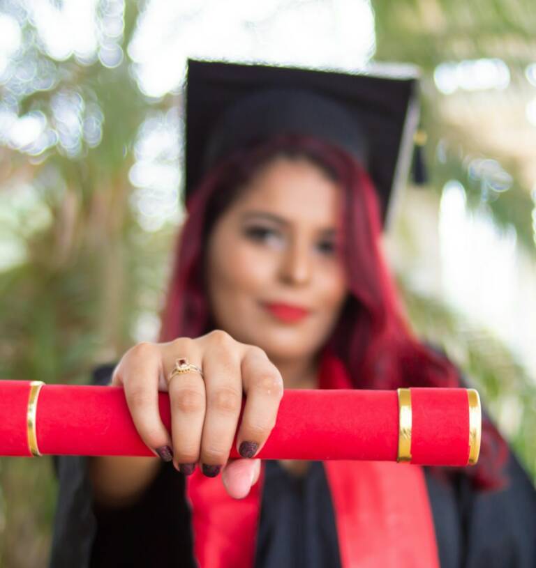 woman in red long sleeve shirt holding red and black academic hat