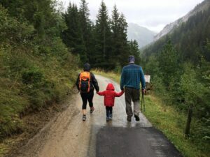 man, woman, and child walking together along dirt road